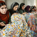 Kashmiri girls working on a carpet through chisels.