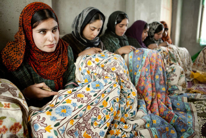 Kashmiri girls working on a carpet through chisels.